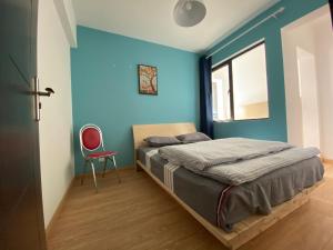 a bedroom with blue walls and a bed with a red chair at 合家欢 in Kunming