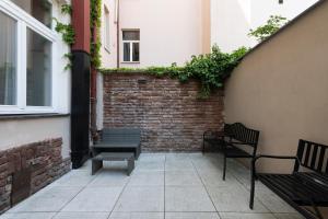 a patio with two benches and a brick wall at numa l Root Rooms & Apartments in Prague