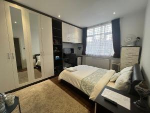 a bedroom with a bed and a desk and a mirror at Deluxe Homestay near Tottenham Hotspur Stadium in London