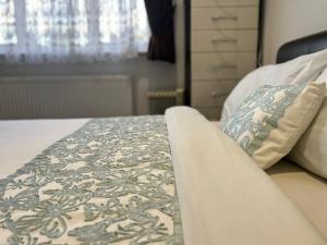 a bed with a blanket and pillows on it at Deluxe Homestay near Tottenham Hotspur Stadium in London