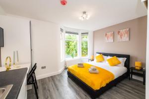 1 dormitorio con 1 cama con sábanas amarillas y ventana en Five Seasons Liverpool City - Modern Studios near Anfield en Liverpool