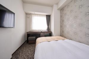 a bedroom with a bed and a window and a desk at Hotel Axia Inn Sapporo Susukino in Sapporo