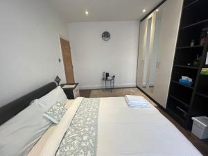 a bedroom with a bed and a clock on the wall at Deluxe Homestay near Tottenham Hotspur Stadium in London