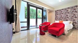 um quarto com cadeiras vermelhas, uma cama e uma televisão em Charming Hostel em Hualien City