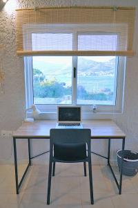 escritorio con ordenador portátil y silla frente a una ventana en Figs & Grapes * Cosy small house * Marmari * South Evia en Marmarion