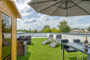 une terrasse avec une table, des chaises et un parasol dans l'établissement Roof Apartment ART-PE, à Trebnje