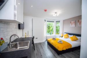 1 dormitorio con 1 cama con sábanas amarillas y lavamanos en Five Seasons Liverpool City - Modern Studios near Anfield en Liverpool