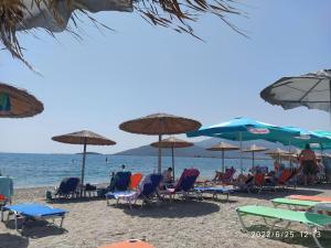 people sitting in chairs and umbrellas on a beach at Ήσυχο οικογενειακό σπίτι. in Astros
