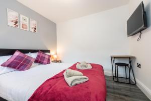 a bedroom with a bed with a red blanket and a tv at Five Seasons Liverpool City - Modern Studios near Anfield in Liverpool