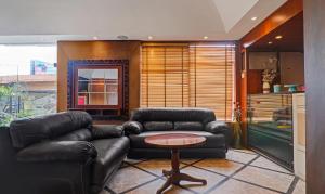 Treebo Trend Edesia في لاكناو: غرفة معيشة مع أريكة جلدية وطاولة