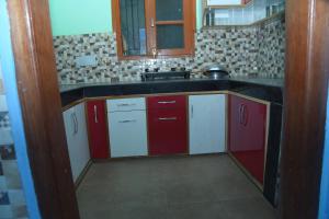 a kitchen with red and white cabinets and a sink at Indu BNB Shimla in Shimla