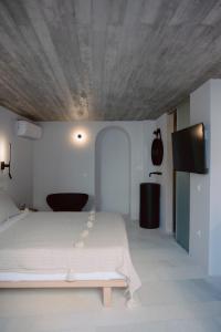 a bedroom with a white bed with a wooden ceiling at Domino Syros by SV in Ermoupoli