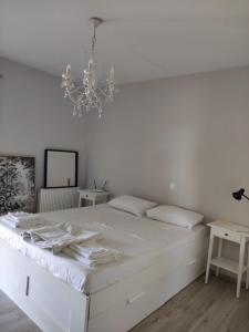 a white bedroom with a white bed and a chandelier at Chálari in Raches