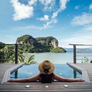 a woman in a hat sitting on a dock looking at the water at Paradise KohYao - SHA Extra Plus in Ko Yao Noi