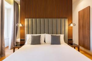 una camera da letto con un grande letto bianco con due cuscini di ELICAL Exclusive Private Suites a Roma
