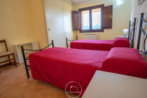 a room with three beds with red sheets and a window at La casa in Terralba