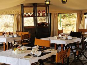 a dining room with white tables and chairs at Serengeti Pioneer Camp in Mugumu