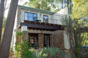 a house with a balcony in the woods at Houtkapperspoort Mountain Cottages in Cape Town