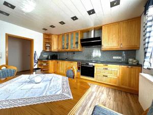 a kitchen with wooden cabinets and a table in it at Ferienwohnung "Auszeit" mit Garten in Riedlhütte