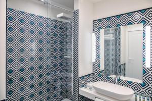 a bathroom with a blue and white tiled wall at Pazziella Garden & Suites in Capri