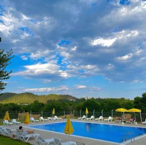 a swimming pool with yellow umbrellas and chairs and a cloudy sky at Dream Town Hotel&Restaurant in Kemer