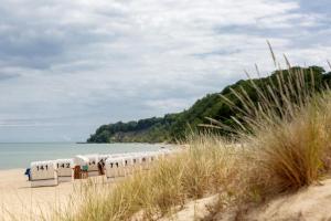a row of beach chairs on a sandy beach at Vju Hotel Rügen in Göhren