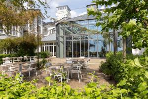a conservatory with tables and chairs in front of a building at Vju Hotel Rügen in Göhren