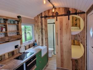 a tiny kitchen with wooden walls and a sink at Rusty - Shepherds hut sleeps up to 4 in Sidlesham