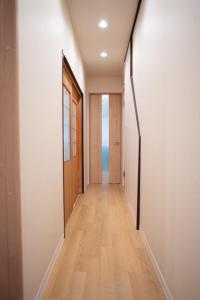a hallway with white walls and a wooden door at HANASTAY花渓居 · 柳（YANAGI) in Osaka