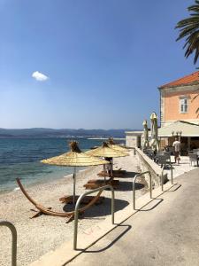 ein Strand mit Stühlen und Sonnenschirmen und das Meer in der Unterkunft Apartments by the sea Orebic, Peljesac - 16883 in Orebić