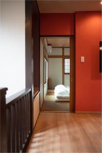 a hallway with a bed in a room with red walls at HANASTAY花渓居 · 柳（YANAGI) in Osaka