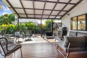 a patio with chairs and a couch and tables at Mudjimba Escape-pet friendly, luxury villa w/ pool in Mudjimba