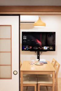 a dining room table with a tv on the wall at HANASTAY花渓居 · 柳（YANAGI) in Osaka