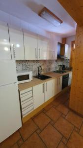 uma cozinha com armários brancos e piso em azulejo em Alojamiento Rural Casa Inocente em La Toba