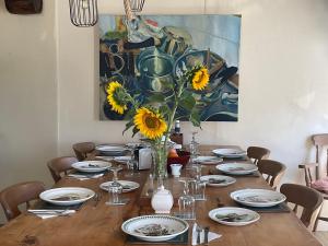 a dining room table with a vase of sunflowers on it at Le Jardin de Rose 24 FEUILLEBERT Romagne 86700 in Romagne
