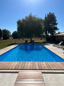 a swimming pool with a wooden deck and a tree at Country villa for 19 pool cinema football pitch in Verteillac