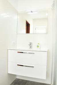 ein weißes Badezimmer mit einem Waschbecken und einem Spiegel in der Unterkunft Appartment Haus Birgit in Seefeld in Tirol