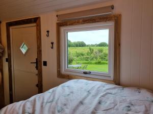 ein Schlafzimmer mit einem Fenster, einem Bett und einem Tisch in der Unterkunft Rusty - Shepherds hut sleeps up to 4 in Sidlesham