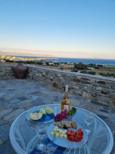 a table with two plates of food and a bottle of wine at ONAR RESIDENCE PAROS in Chrissi Akti