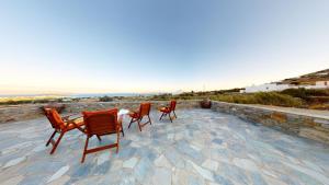 drie stoelen en een tafel op een patio met uitzicht op de oceaan bij ONAR RESIDENCE PAROS in Chrissi Akti