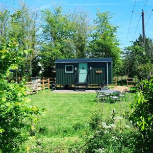 ein kleines grünes Haus in einem Hof mit Picknicktisch in der Unterkunft Rusty - Shepherds hut sleeps up to 4 in Sidlesham