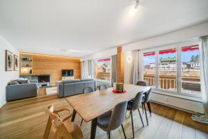 a dining room and living room with a wooden table and chairs at In the heart of Crans, fireplace and parking in Crans-Montana