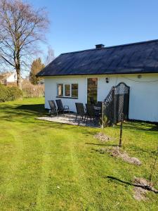una casa blanca con sillas en el patio en Pensionat Strandhuset i Abbekås en Abbekås