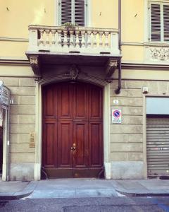 a building with a wooden door with a balcony above it at Le Affinità Selettive in Turin