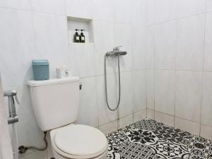 y baño con aseo blanco y ducha. en 37 Guesthouse, en Yakarta