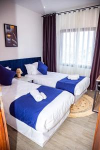 Cette chambre comprend 2 lits avec des draps bleus et blancs. dans l'établissement Yvanka Appart'City Antsirabe, à Antsirabe