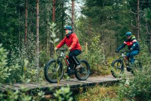 two men riding bikes on a wooden trail at Pajulahti Olympic & Paralympic Training Center in Nastola