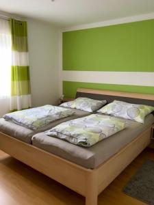 two beds in a bedroom with a green wall at Ferienwohnung am Mattsee in Guggenberg