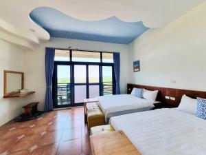 1 dormitorio con 2 camas y ventana grande en Warm & Cozy Inn, en Hengchun