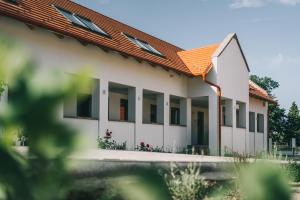 un bâtiment blanc avec un toit orange dans l'établissement Kardamom Studio Apartman, à Szigliget
